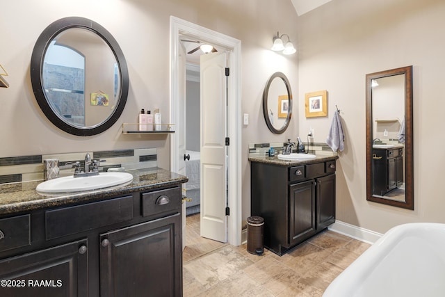 full bathroom featuring two vanities, a soaking tub, and a sink