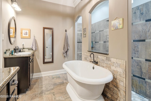 full bathroom featuring baseboards, a freestanding tub, vanity, and tiled shower