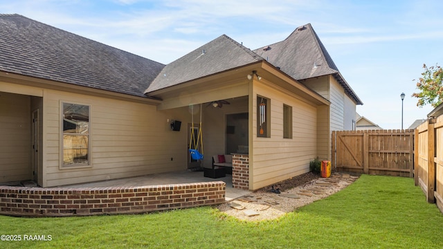 rear view of house featuring a yard, roof with shingles, a patio, and fence