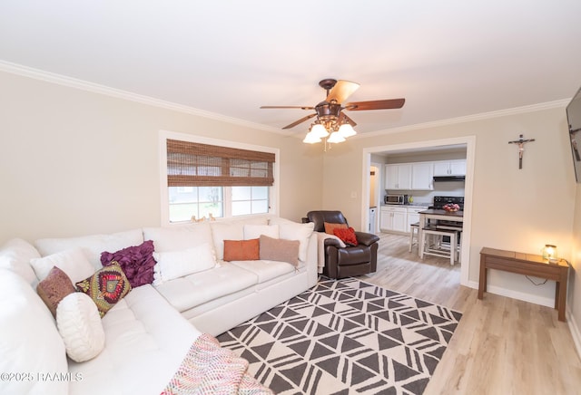 living room with crown molding, light wood-style flooring, ceiling fan, and baseboards