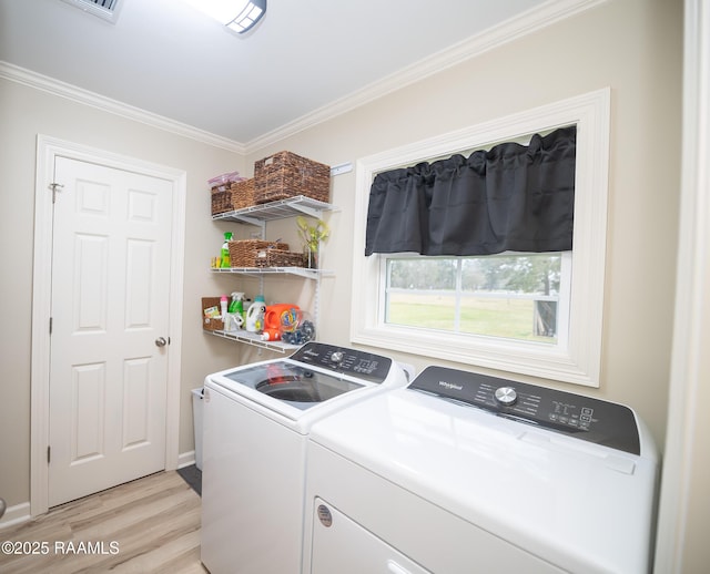 clothes washing area featuring washer and dryer, laundry area, light wood finished floors, and ornamental molding