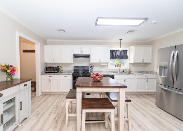 kitchen featuring stainless steel appliances, under cabinet range hood, visible vents, and a sink