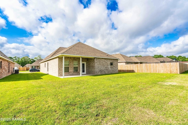 rear view of property with brick siding, a lawn, a patio, and fence