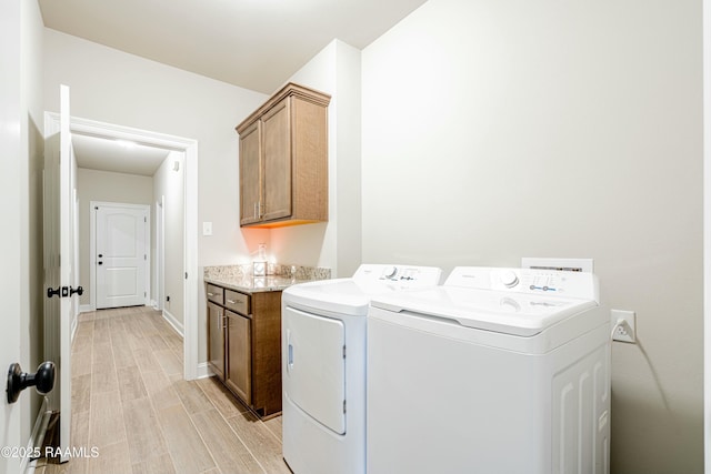 clothes washing area featuring washing machine and clothes dryer, cabinet space, light wood finished floors, and baseboards