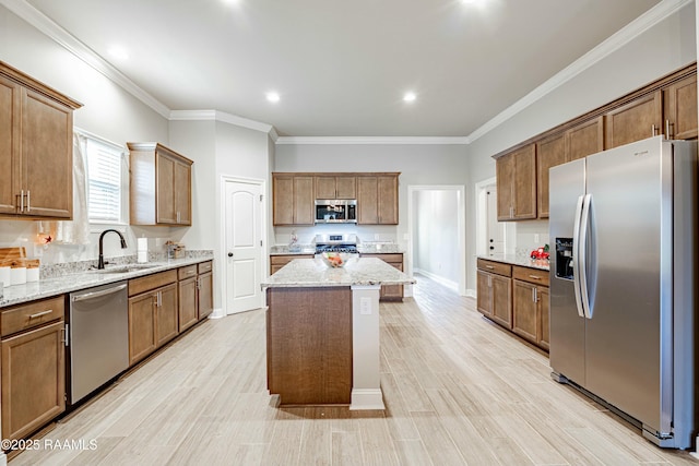 kitchen featuring crown molding, stainless steel appliances, a kitchen island, and a sink
