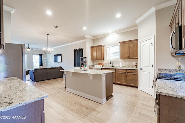 kitchen with a sink, open floor plan, visible vents, appliances with stainless steel finishes, and ornamental molding
