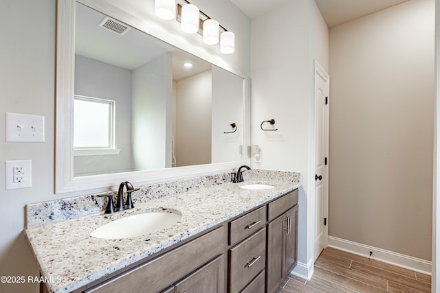 bathroom featuring wood finished floors, visible vents, baseboards, and a sink