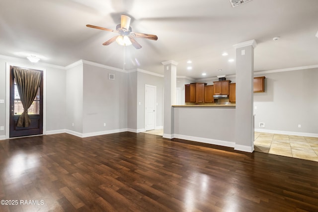unfurnished living room with baseboards, a ceiling fan, crown molding, ornate columns, and wood finished floors