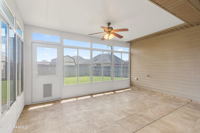 unfurnished sunroom featuring tile patterned floors, ceiling fan, and a wealth of natural light