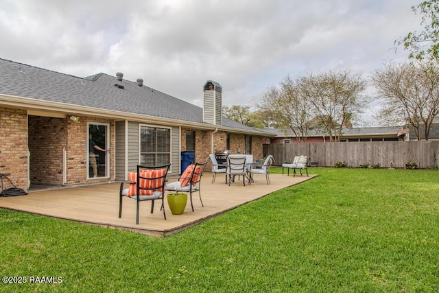 back of house with a wooden deck, a lawn, fence, brick siding, and a chimney