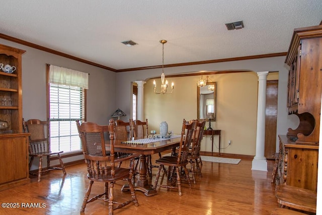 dining area featuring visible vents, light wood-type flooring, and ornate columns