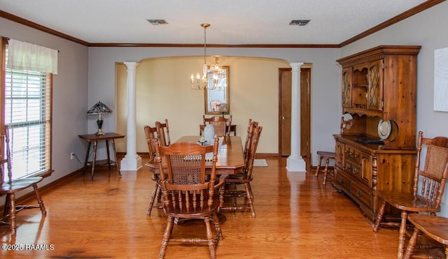 dining room with light wood finished floors, decorative columns, a notable chandelier, and visible vents
