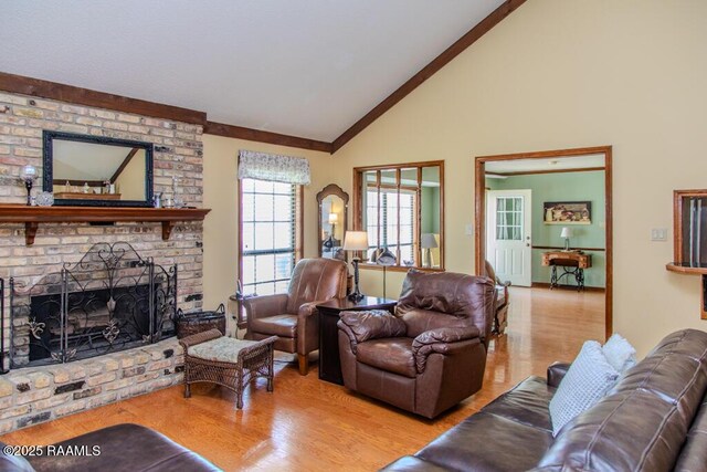 living area with wood finished floors, high vaulted ceiling, and a brick fireplace