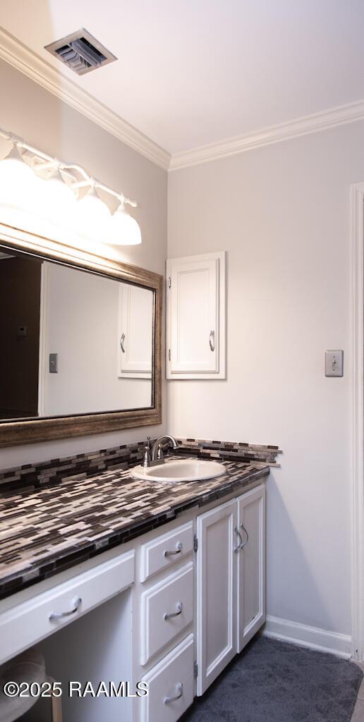 bathroom with vanity, baseboards, ornamental molding, and visible vents