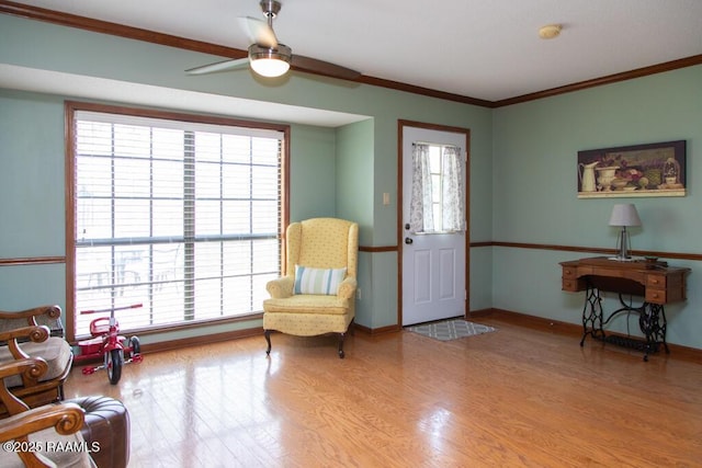 sitting room featuring ornamental molding, baseboards, a ceiling fan, and wood finished floors