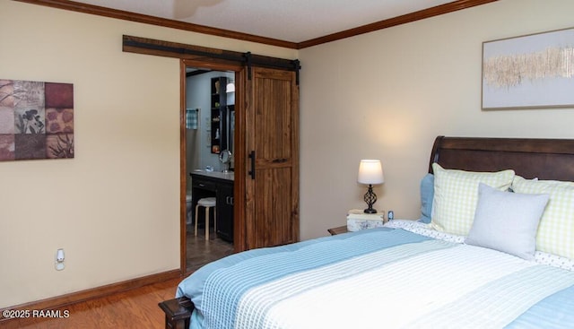 bedroom with baseboards, crown molding, connected bathroom, a barn door, and wood finished floors