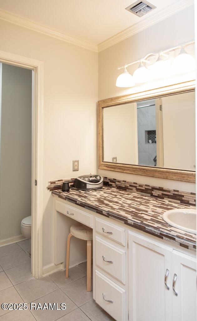 bathroom with tile patterned flooring, vanity, visible vents, and ornamental molding