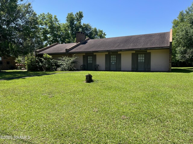 8133 Meadow Ln, Abbeville, LA 70510 - ranch-style home with stucco siding, a chimney, and a front yard