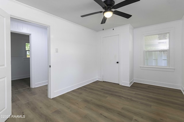 unfurnished bedroom featuring a closet, ornamental molding, baseboards, and dark wood finished floors