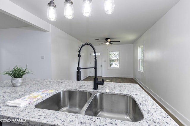 room details with baseboards, light stone counters, a ceiling fan, decorative light fixtures, and a sink