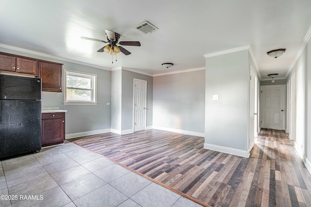 kitchen with freestanding refrigerator, ornamental molding, a ceiling fan, visible vents, and baseboards