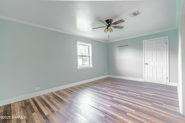spare room featuring wood finished floors, ceiling fan, ornamental molding, and visible vents
