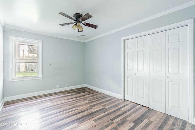 unfurnished bedroom with wood finished floors, a closet, ornamental molding, and baseboards