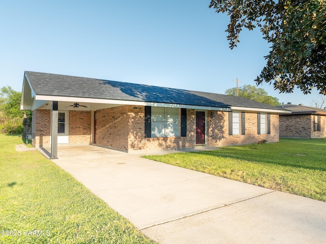 ranch-style house featuring a ceiling fan, brick siding, a front lawn, an attached carport, and driveway