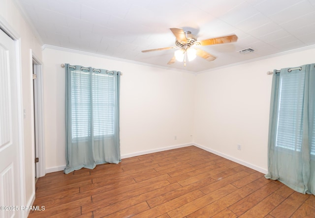 empty room featuring visible vents, baseboards, ornamental molding, ceiling fan, and wood finished floors