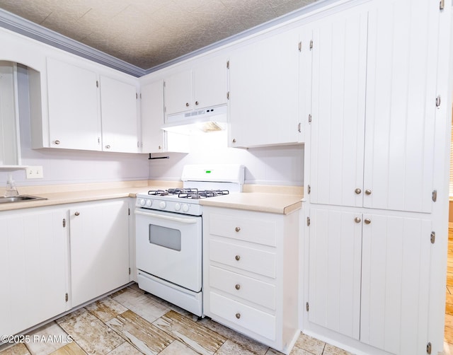 kitchen featuring crown molding, white range with gas stovetop, white cabinets, under cabinet range hood, and light countertops