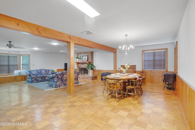 1119 Mary Lee St, Franklin, LA 70538 - dining area with visible vents, a wainscoted wall, wooden walls, a fireplace, and ceiling fan with notable chandelier
