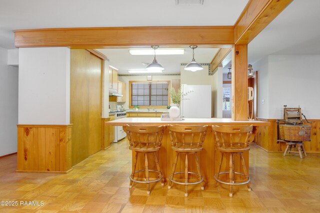 1119 Mary Lee St, Franklin, LA 70538 - kitchen featuring a breakfast bar area, range, light countertops, a wainscoted wall, and under cabinet range hood