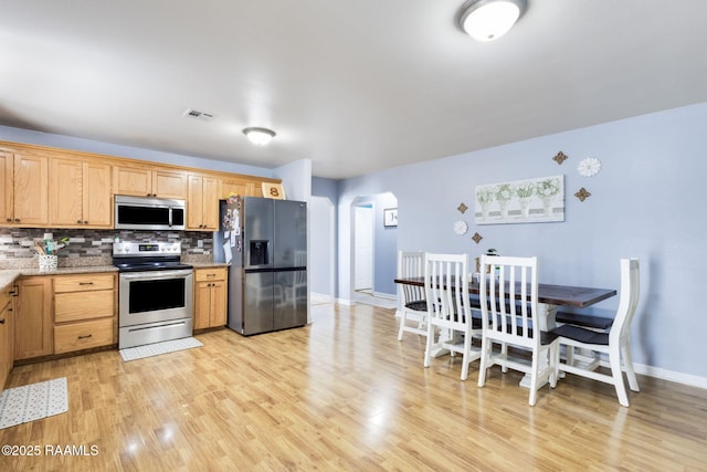 197 John Paul Dr, Opelousas, LA 70570 - kitchen featuring visible vents, arched walkways, stainless steel appliances, light wood-style flooring, and decorative backsplash
