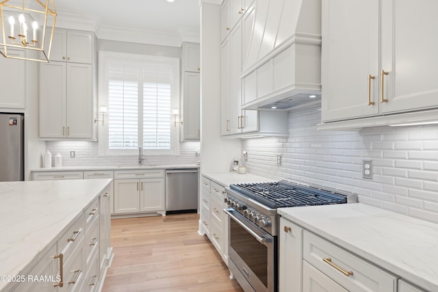 211 Crossbill Dr, Lafayette, LA 70508 - kitchen featuring crown molding, a chandelier, stainless steel appliances, light wood-style flooring, and premium range hood