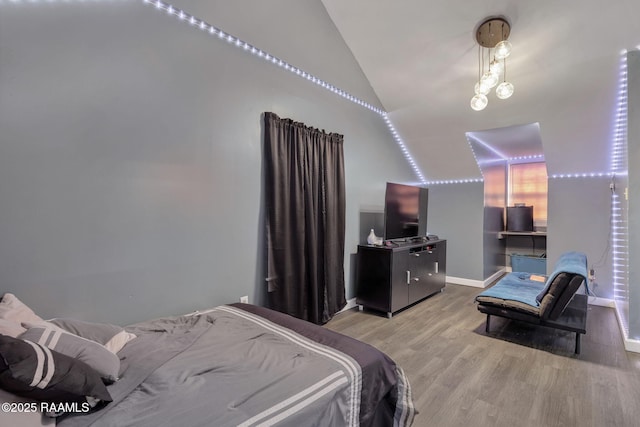 bedroom with light wood-style floors, baseboards, and lofted ceiling