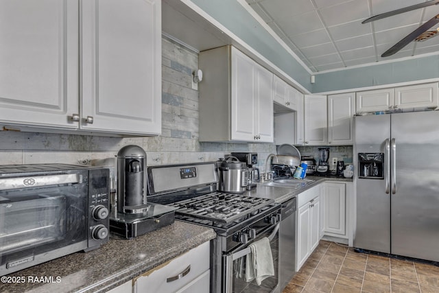 kitchen with a toaster, white cabinetry, backsplash, appliances with stainless steel finishes, and a sink