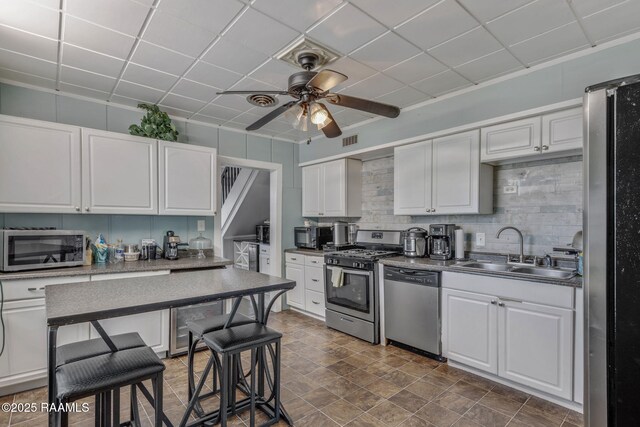kitchen with visible vents, white cabinets, a sink, a ceiling fan, and stainless steel appliances