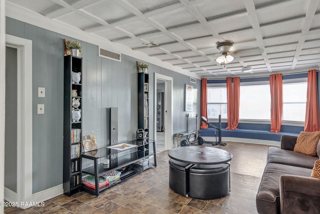 living room with wooden walls, visible vents, baseboards, and ceiling fan