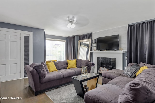 living area featuring wood finished floors, ceiling fan, and a fireplace