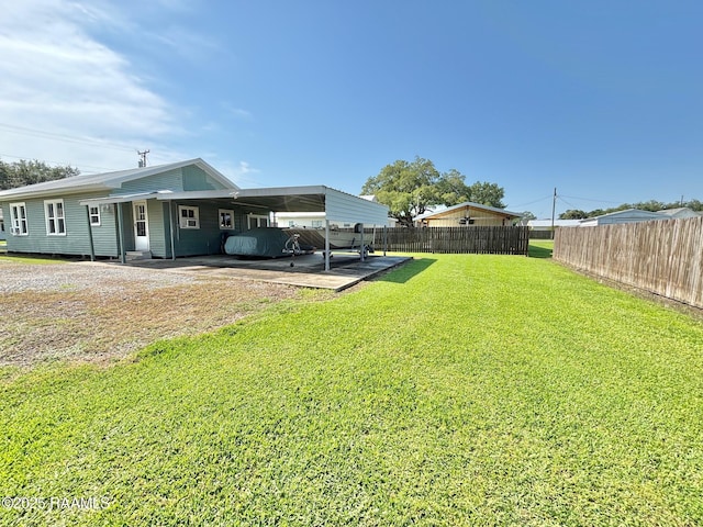 view of yard with fence, driveway, and a carport