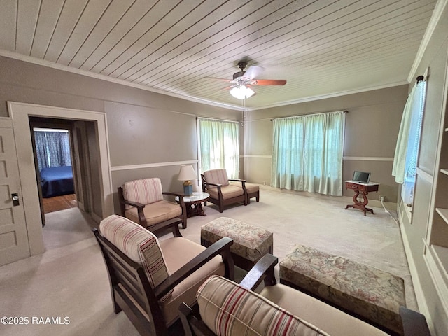 living area with carpet floors, ornamental molding, ceiling fan, and wooden ceiling
