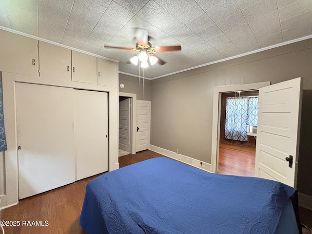 bedroom featuring a closet, ornamental molding, a ceiling fan, and wood finished floors