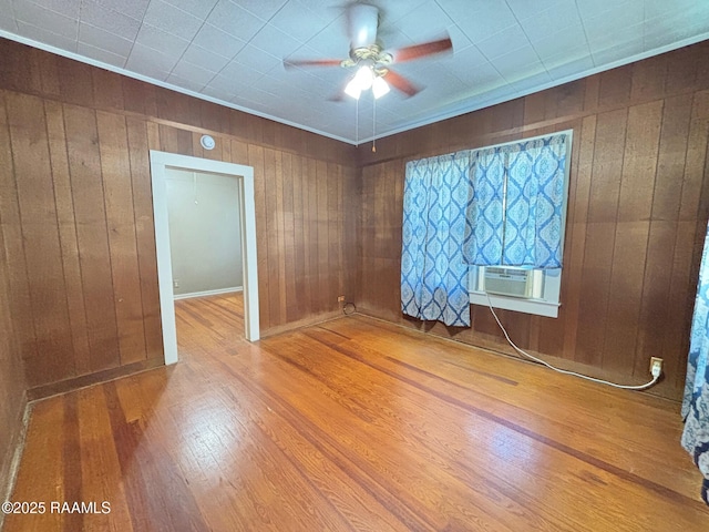 spare room with ceiling fan, wood walls, wood finished floors, and cooling unit
