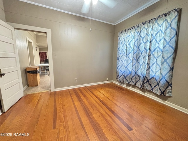 empty room with baseboards, ornamental molding, ceiling fan, and wood finished floors