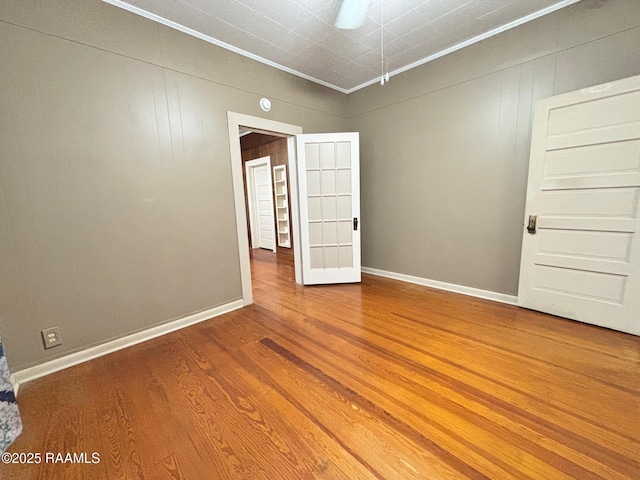 unfurnished room featuring baseboards, ornamental molding, and wood finished floors