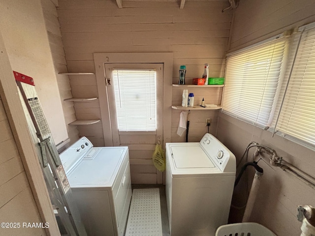 laundry area featuring laundry area, washer and clothes dryer, light floors, and wood walls