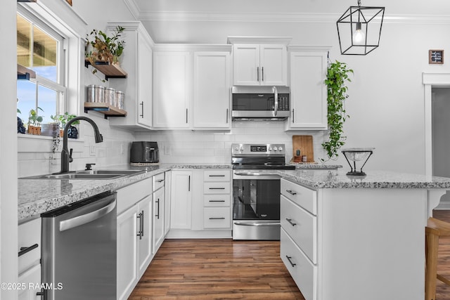 kitchen featuring backsplash, crown molding, a kitchen island, stainless steel appliances, and a sink