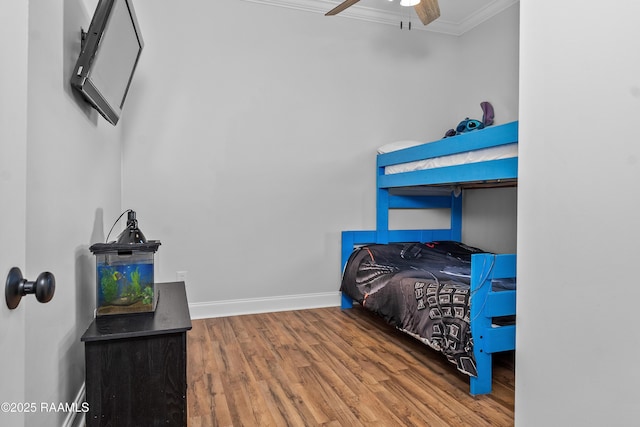 bedroom with crown molding, wood finished floors, ceiling fan, and baseboards