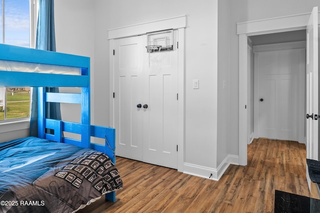 bedroom with a closet, baseboards, and wood finished floors