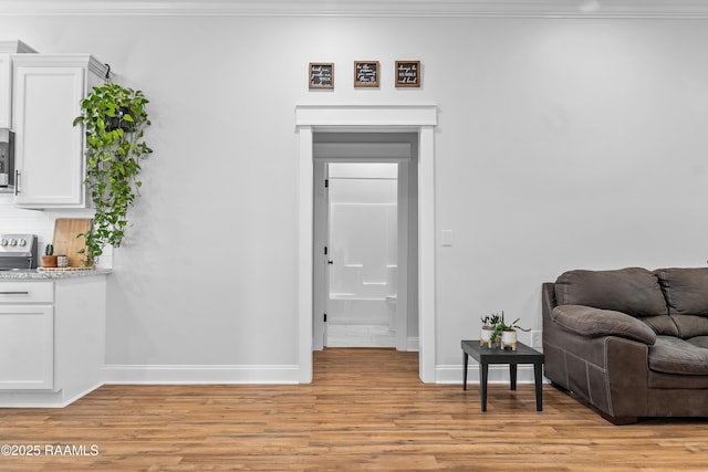 sitting room featuring light wood finished floors, baseboards, and crown molding